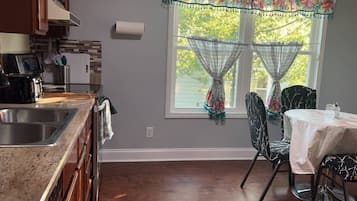 Une cuisine équipée d’un évier, d’une cuisinière et d’un coin repas avec des chaises et une table.