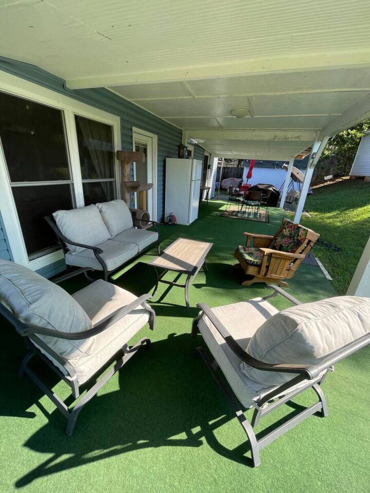 Un patio couvert avec des meubles d’extérieur, un réfrigérateur et une vue sur le jardin arrière.