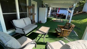 A covered patio with outdoor furniture, a refrigerator, and a view of a backyard.