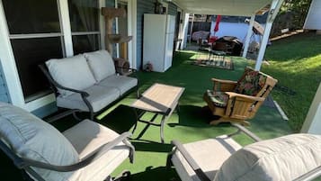 Un patio couvert avec des meubles d’extérieur, un réfrigérateur et une vue sur le jardin arrière.