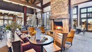 A spacious indoor seating area with a stone fireplace, leather seating, and a menu on a table.
