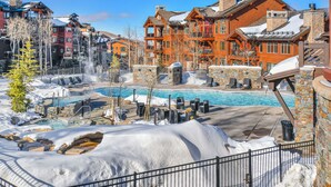 A resort with a pool, snow-covered landscape, and multiple buildings with balconies.