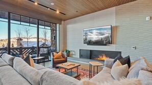 A modern living room with a fireplace, large windows, and a cozy seating area.