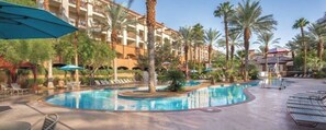 A hotel pool area with multiple pools, palm trees, and lounge chairs. - Awesome 2 Bedroom Condo for Formula 1 (Las Vegas)
