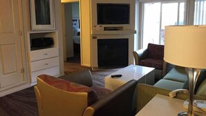 Ein Hotelzimmer mit Fernseher, Kamin, Sofa und Lampe.