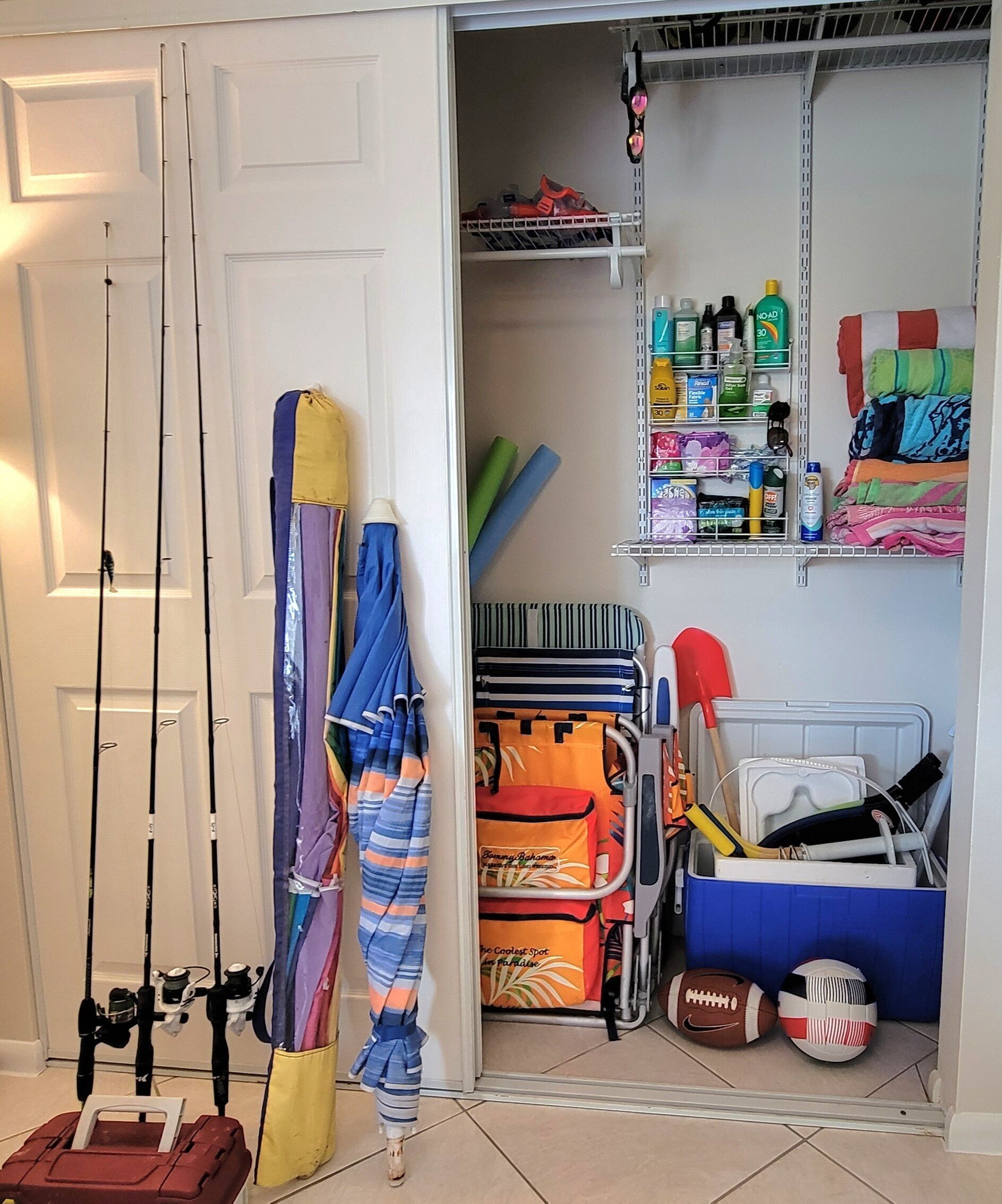 A storage area with fishing rods, umbrellas, and a cooler with sports equipment.