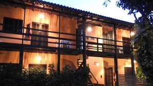 A two-story building with a balcony and a staircase leading to the upper floor. - Recanto Primavera - Camburi (São Sebastião)