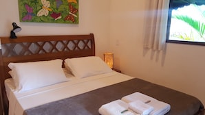A neatly made bed with white linens, a brown headboard, and a decorative butterfly painting above it. - Recanto Primavera - Camburi (São Sebastião)