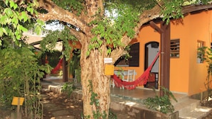 A tree with a hammock and a sign indicating a kitchen area. - Recanto Primavera - Camburi (São Sebastião)