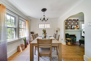Un coin repas avec une table en bois dressée pour quatre personnes, entourée de chaises, et un lustre au-dessus.