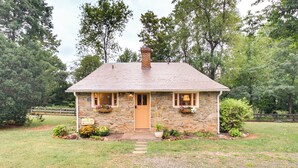 A stone house with a wooden door, a chimney, and a small front porch. - Monticello Wine Trail Cottage - Close to Hiking! (Afton)