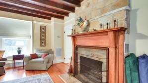 A living room with a stone fireplace, wooden flooring, and a patterned rug. - Monticello Wine Trail Cottage - Close to Hiking! (Afton)