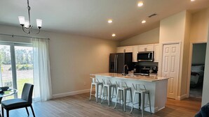 Una cocina moderna con una isla central, taburetes de bar y un comedor con mesa y sillas.