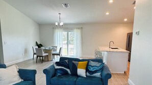 Una sala moderna con un sofá azul, un comedor y una cocina.