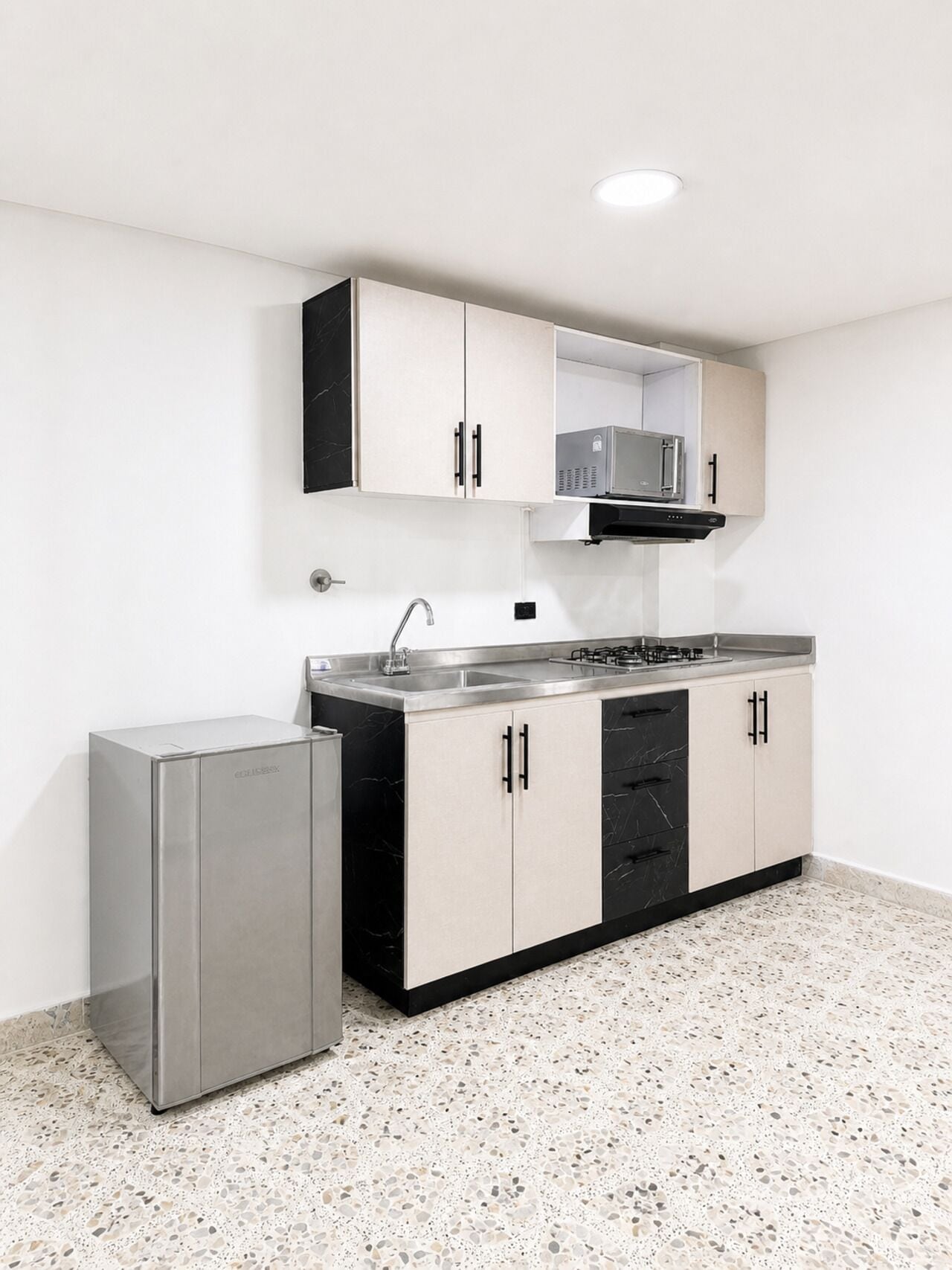Una cocina funcional con refrigerador, microondas y pileta.