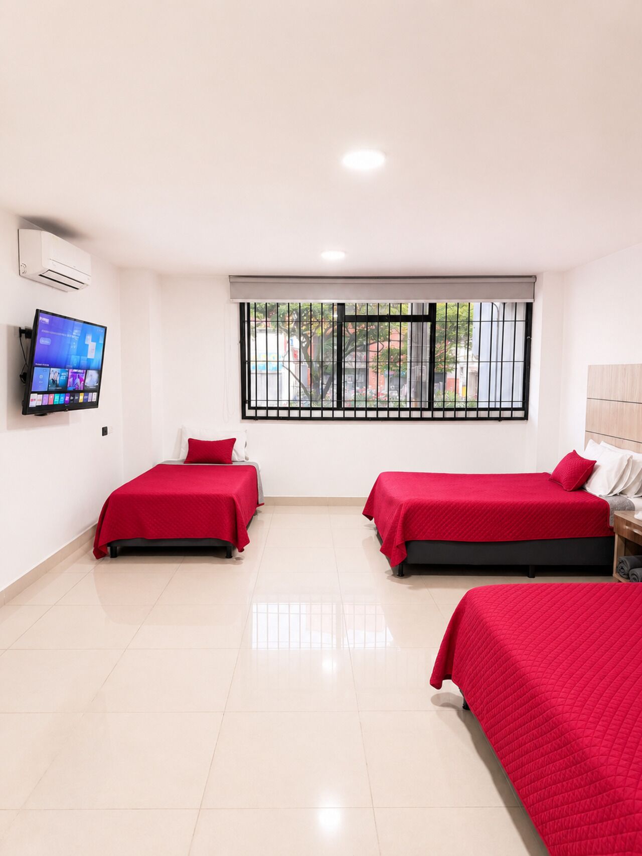A hotel room with two beds, a TV, and a window with a view of the outside.