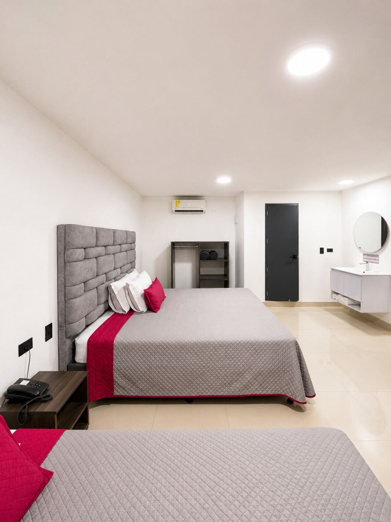 A modern bedroom with a large bed, bedside tables, a wardrobe, a mirror, and a small desk with a chair.