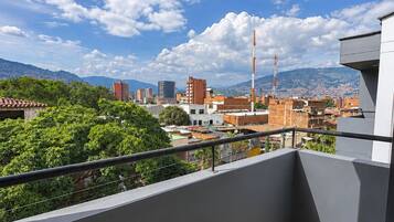 A balcony with a view of a cityscape, including buildings and mountains.