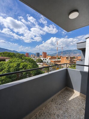 A balcony with a view of a cityscape, including buildings and mountains. - Hotel Ofix - Laureles (Medellín)