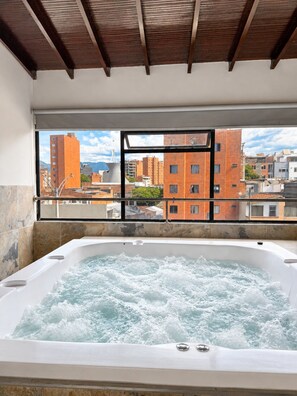 Un jacuzzi con vista a la ciudad a través de la barandilla de un balcón.