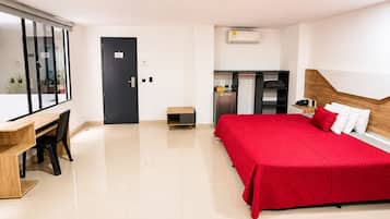 Une chambre d’hôtel comprenant un lit, un bureau, un petit coin cuisine et une salle de bain avec baignoire.