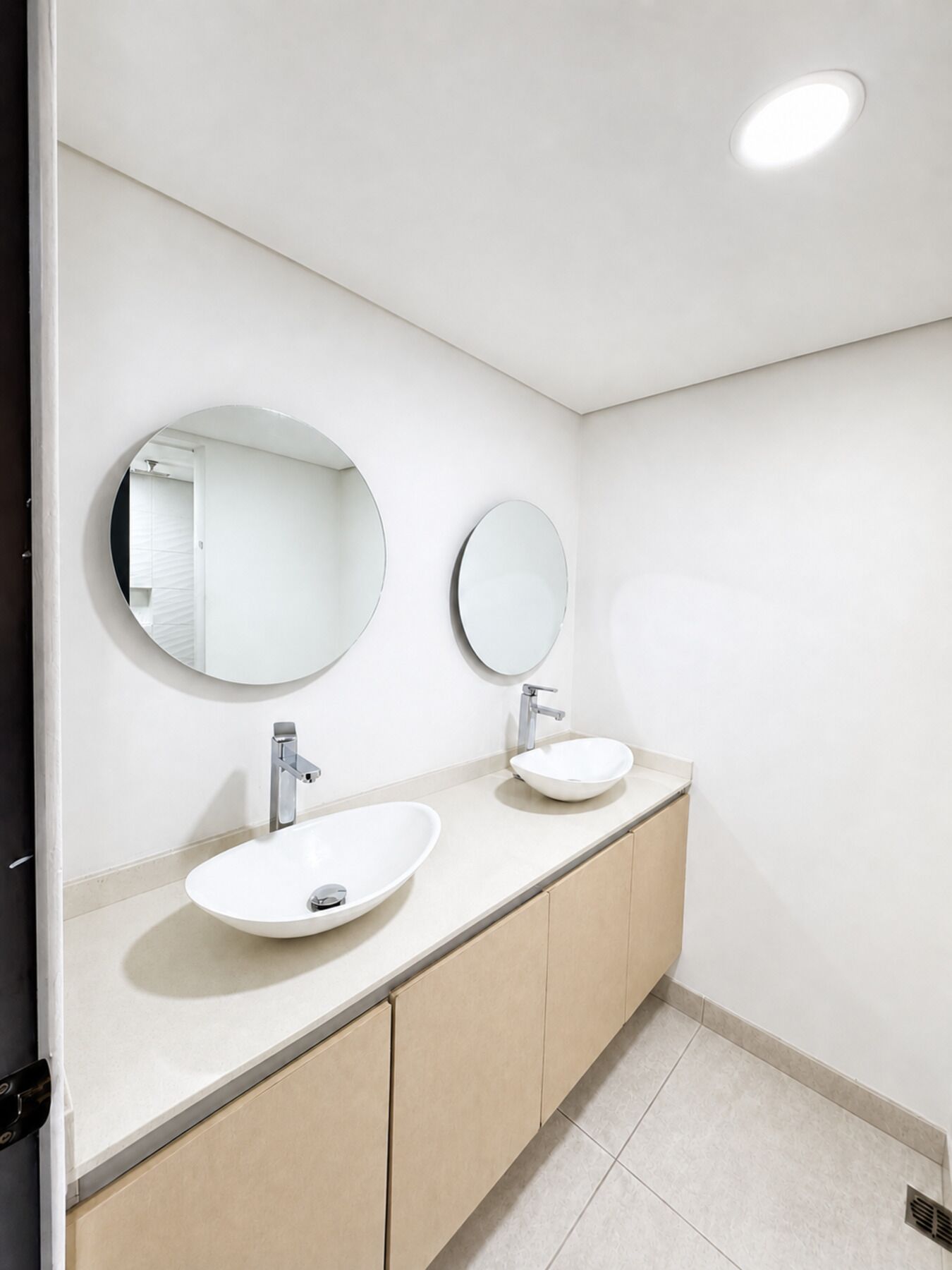 A modern bathroom with two sinks, a mirror, and a light fixture.