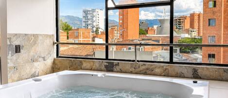 A hot tub with a view of a cityscape through a window.
