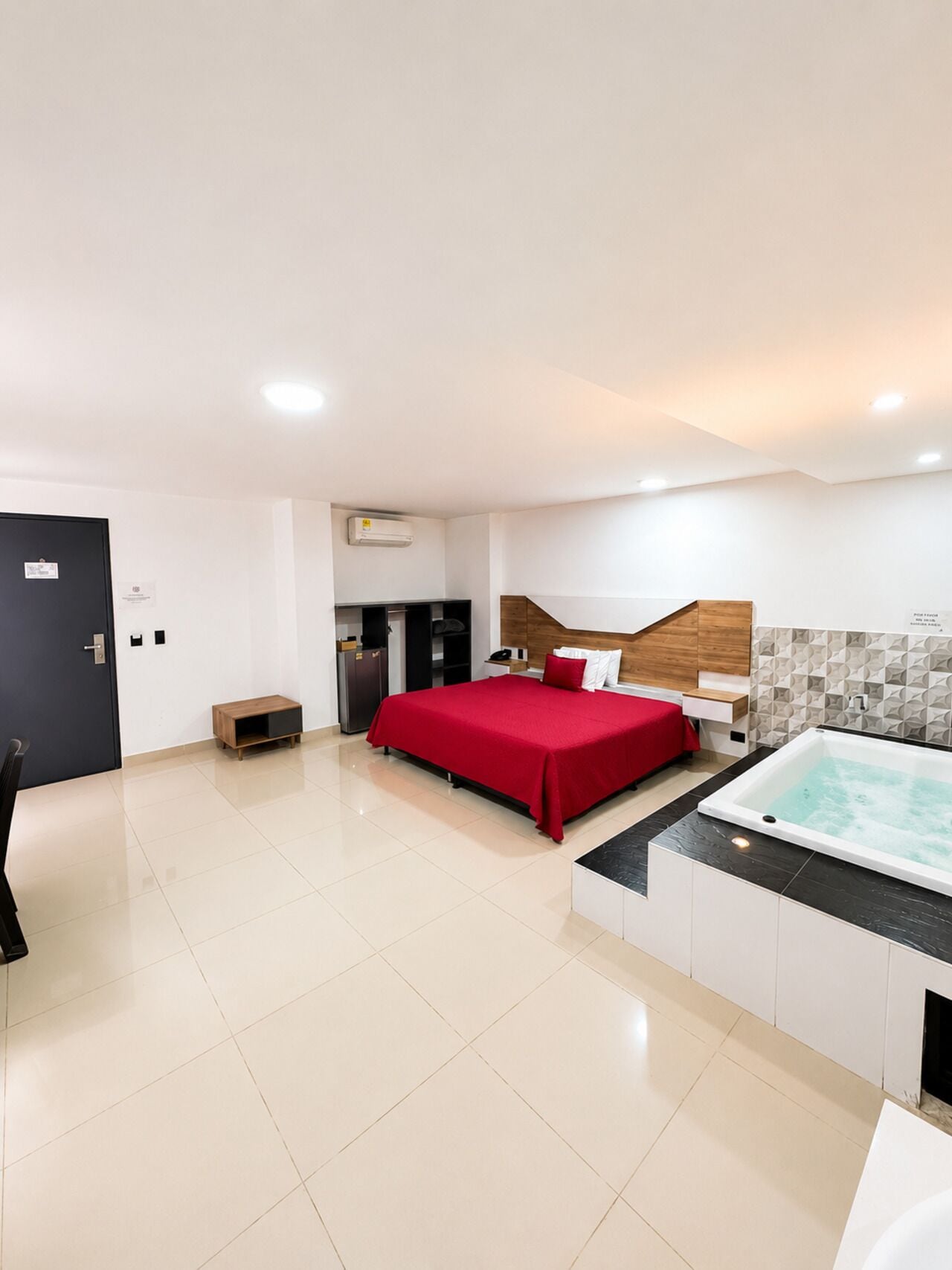 A hotel room with a bed, a small desk, a bench, a bathtub, and a wardrobe.