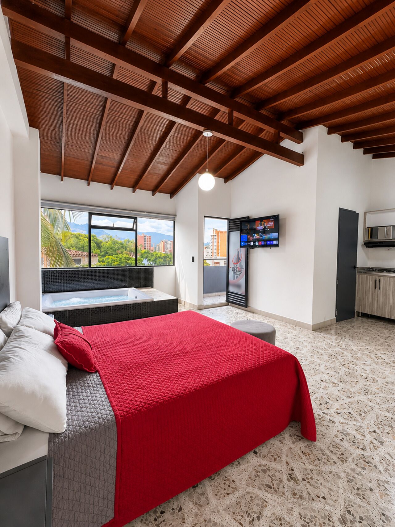 Ein Schlafzimmer mit einem großen Bett, einem Fernseher und Blick auf die Stadt.