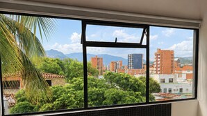 A bathroom with a bathtub, a window with a view of a cityscape, and a tiled backsplash. - Hotel Ofix - Laureles (Medellín)