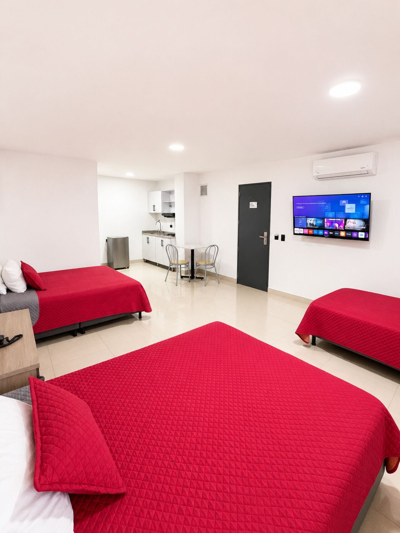 Une chambre d’hôtel avec deux lits, une kitchenette, une télévision et une porte.