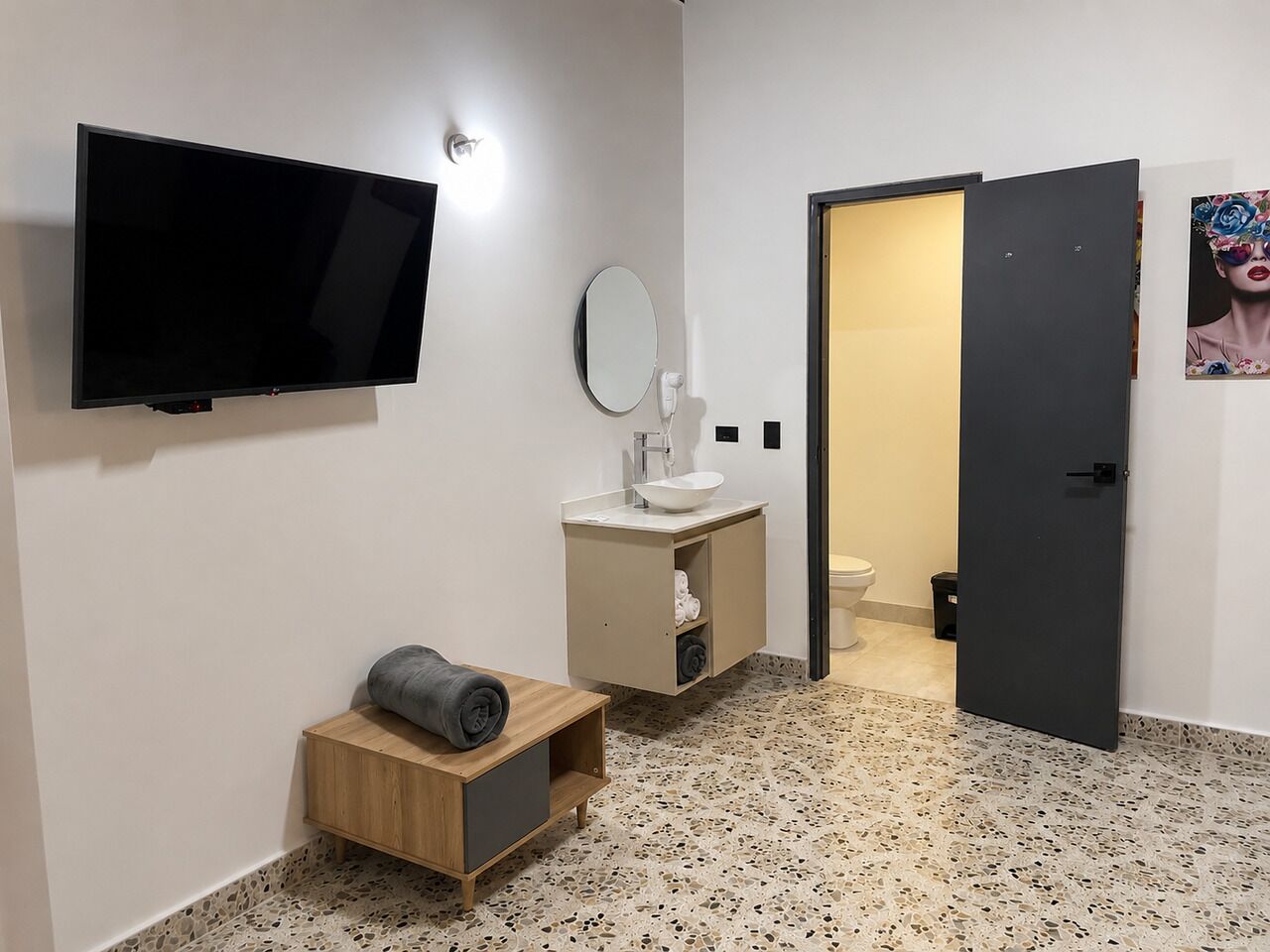 A modern bathroom with a flat-screen TV, a mirror, a sink, and a toilet.