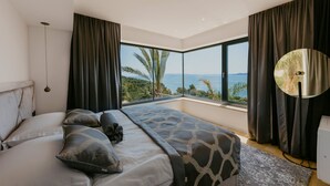 A bedroom with a large bed, a view of the sea, and a round mirror. - Villa Black & Gold with Pool (Okrug Gornji)
