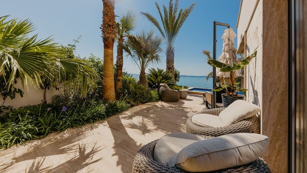 A sunlit outdoor seating area with wicker furniture and a view of the sea. - Villa Black & Gold with Pool (Okrug Gornji)