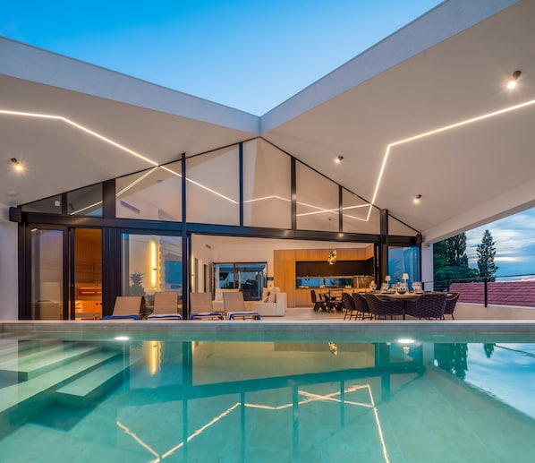 Une maison moderne dotée d’une piscine, d’un coin repas et d’une cuisine.
