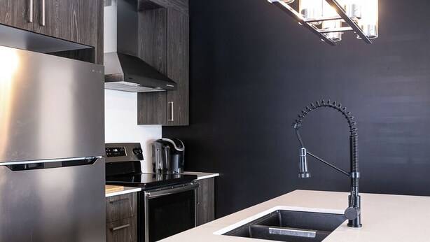 A modern kitchen with dark wood cabinets, stainless steel appliances, and a sleek black faucet.
