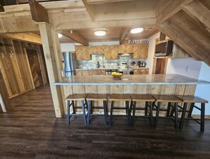 Una cucina con mobili in legno, un piano di lavoro in marmo e un'isola centrale con sgabelli da bar.
