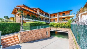 A multi-story residential building with balconies, a stone wall, and a small bridge. - Annamaria 9 con Piscina by Wonderful Italy (Sirmione)