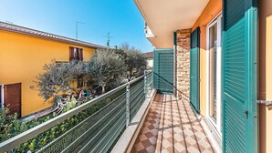 A balcony with a tiled floor, a metal railing, and a view of neighboring buildings. - Annamaria 9 con Piscina by Wonderful Italy (Sirmione)