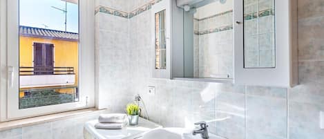 A modern bathroom with a built-in washing machine, a sink, and a large mirror.
