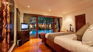 A bedroom with a large bed, a television, and a view of an outdoor swimming pool. - Nice Spacious 3BR Family Villa Walk to Sanur Beach (Sanur)