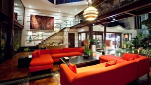 A spacious lobby with a red sectional sofa, a staircase, and a large window overlooking a pool. - Nice Spacious 3BR Family Villa Walk to Sanur Beach (Sanur)