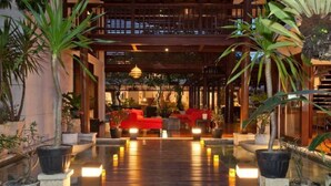 A well-lit outdoor area with a wooden deck, potted plants, and a red seating area. - Nice Spacious 3BR Family Villa Walk to Sanur Beach (Sanur)