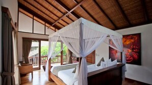 A bedroom with a canopy bed, wooden flooring, a large window, and a painting on the wall. - Nice Spacious 3BR Family Villa Walk to Sanur Beach (Sanur)