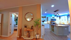 Una cocina moderna con armarios blancos, una isla central y luces colgantes.