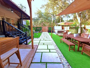 Un patio con piso de madera, mobiliario exterior y una zona de barbacoa.
