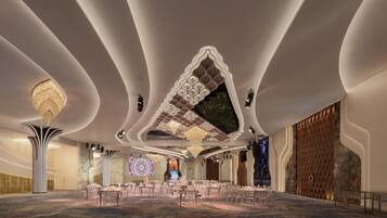 A spacious banquet hall with tiered seating, a large chandelier, and a modern ceiling design.