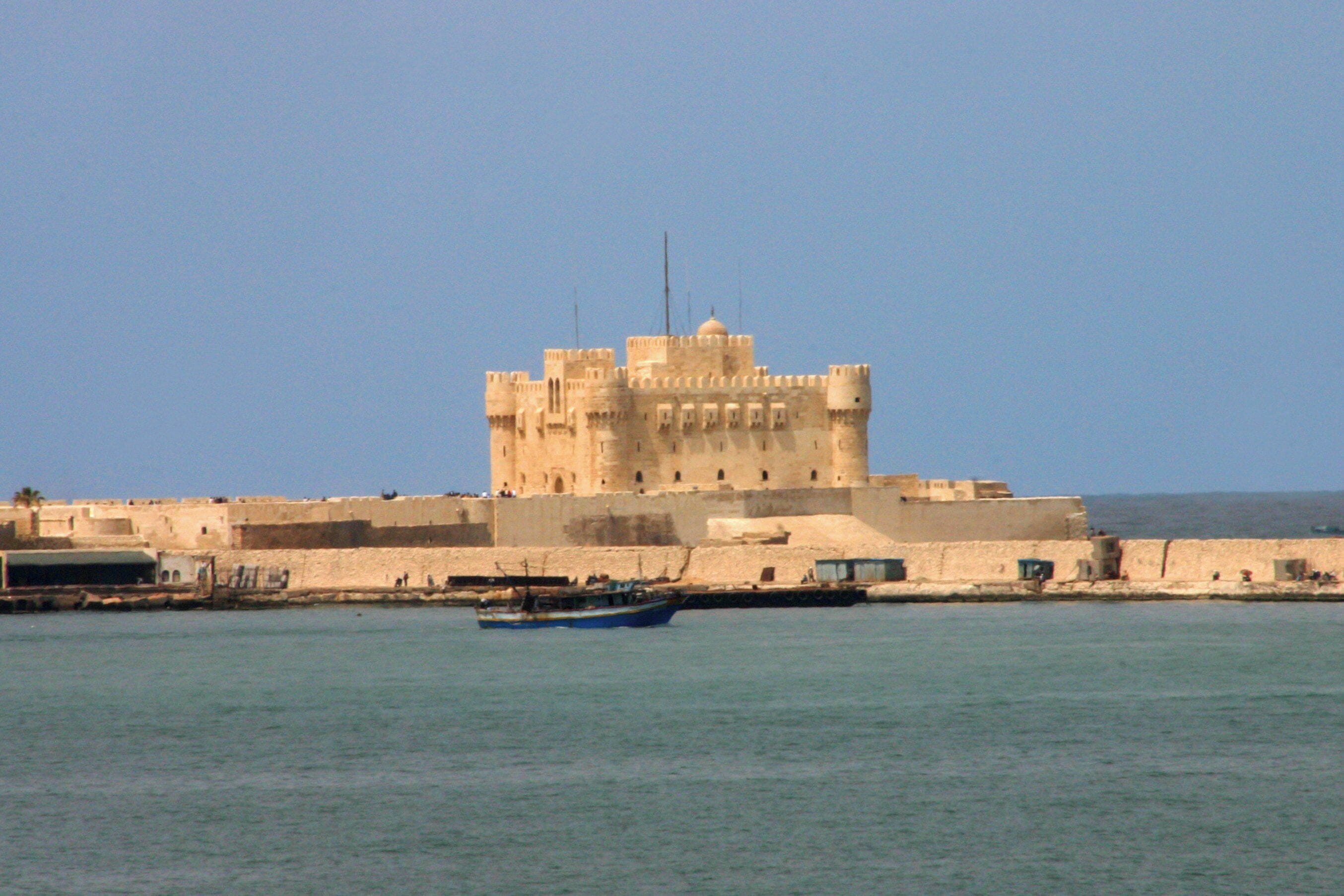 A large, fortified building with a tower, situated by the water.