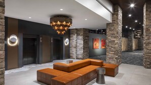 A modern lobby with a sectional sofa, stone walls, and a chandelier. - Red Hawk Resort & Casino (Placerville)