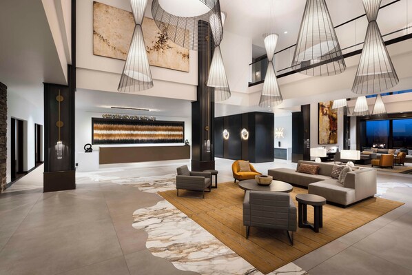 Un vestíbulo amplio con mobiliario moderno, piso de mármol e iluminación contemporánea.